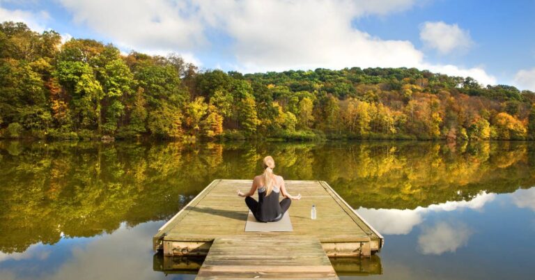 Person practicing mindfulness outdoors, sitting peacefully in nature to stay calm and balanced